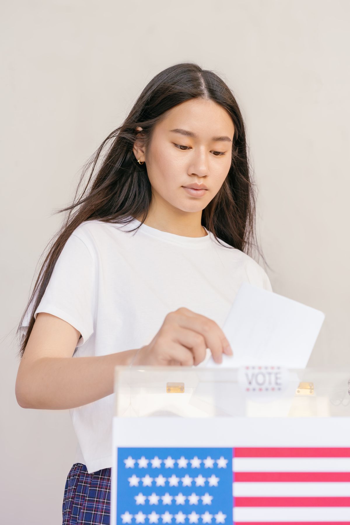 A young woman drops her ballot into a ballot box